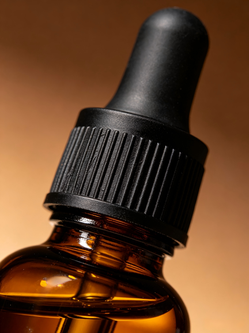 Amber glass essential oil dropper bottle macro closeup, black rubber pipette cap texture
